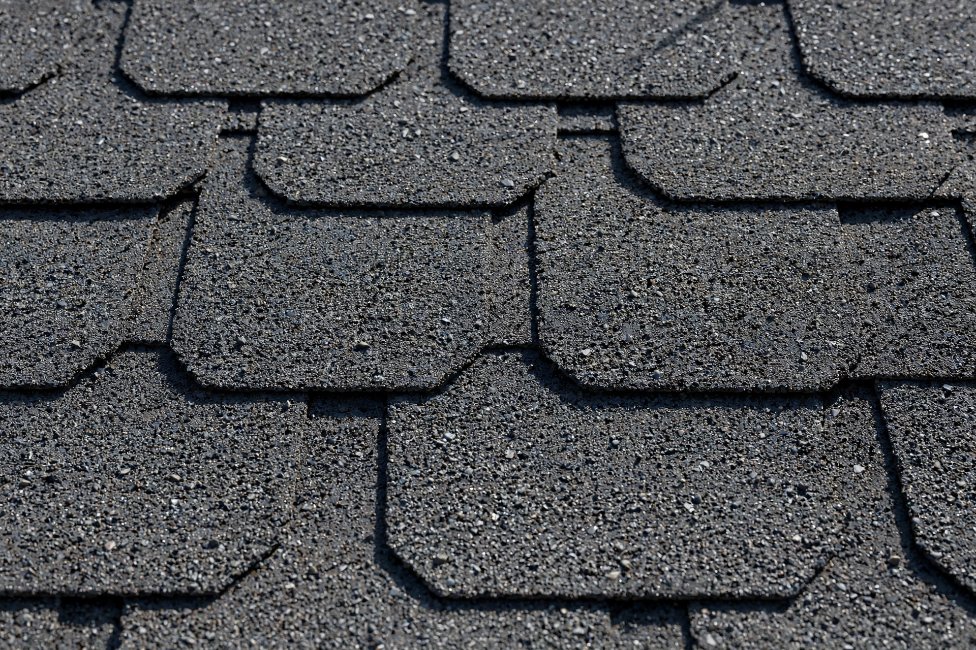 Close-up of dark gray asphalt shingles with granule texture
